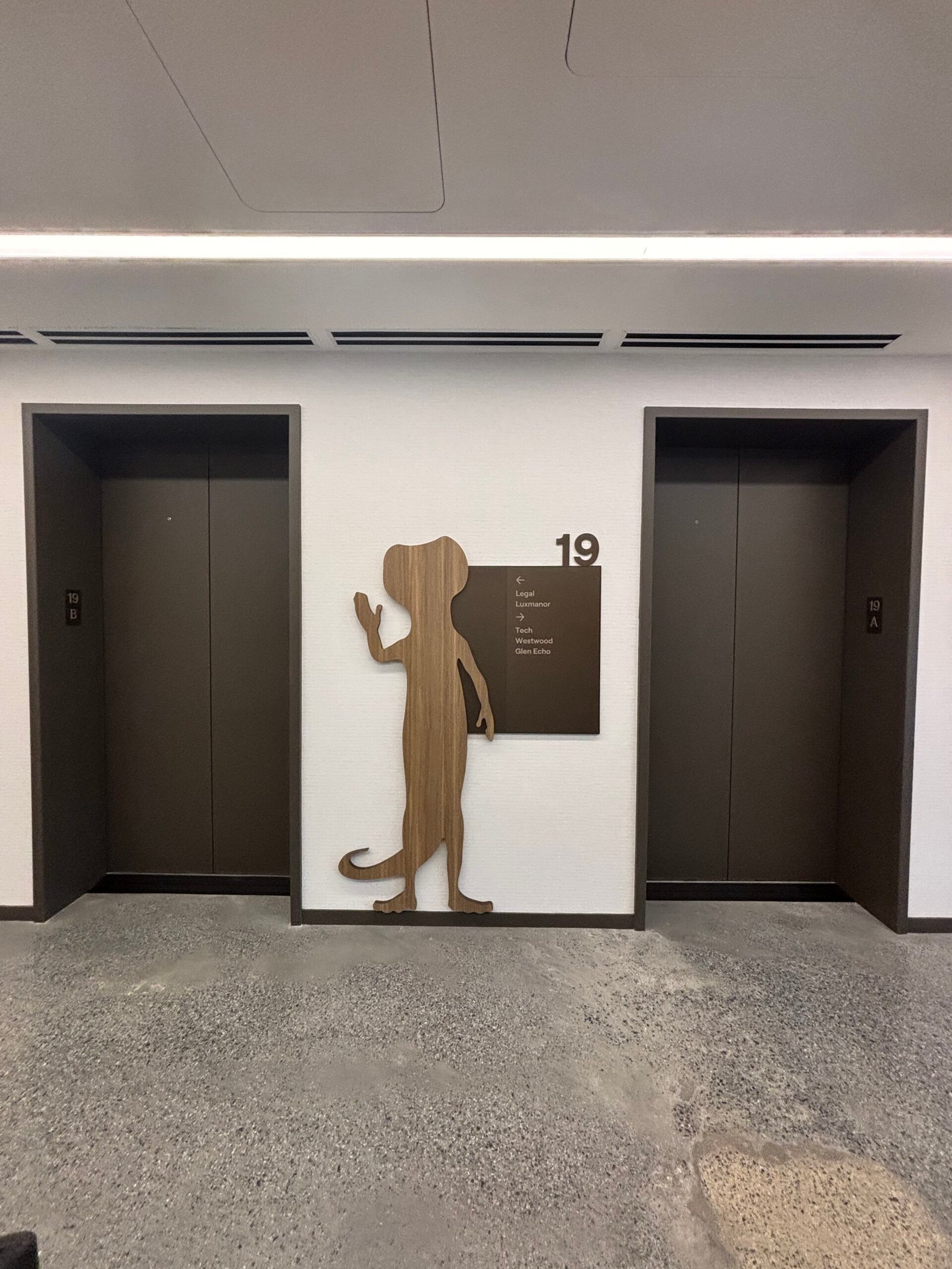 Dimensional wooden wayfinding figure between two elevators